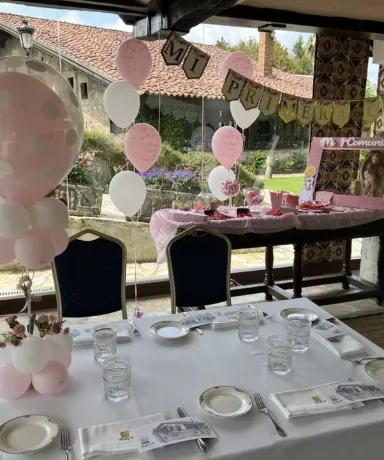 Mesa de restaurante con globos y mesa de dulces detrás