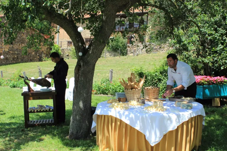 Mesa de quesos junto a mesa con cortador de jamón en un jardín